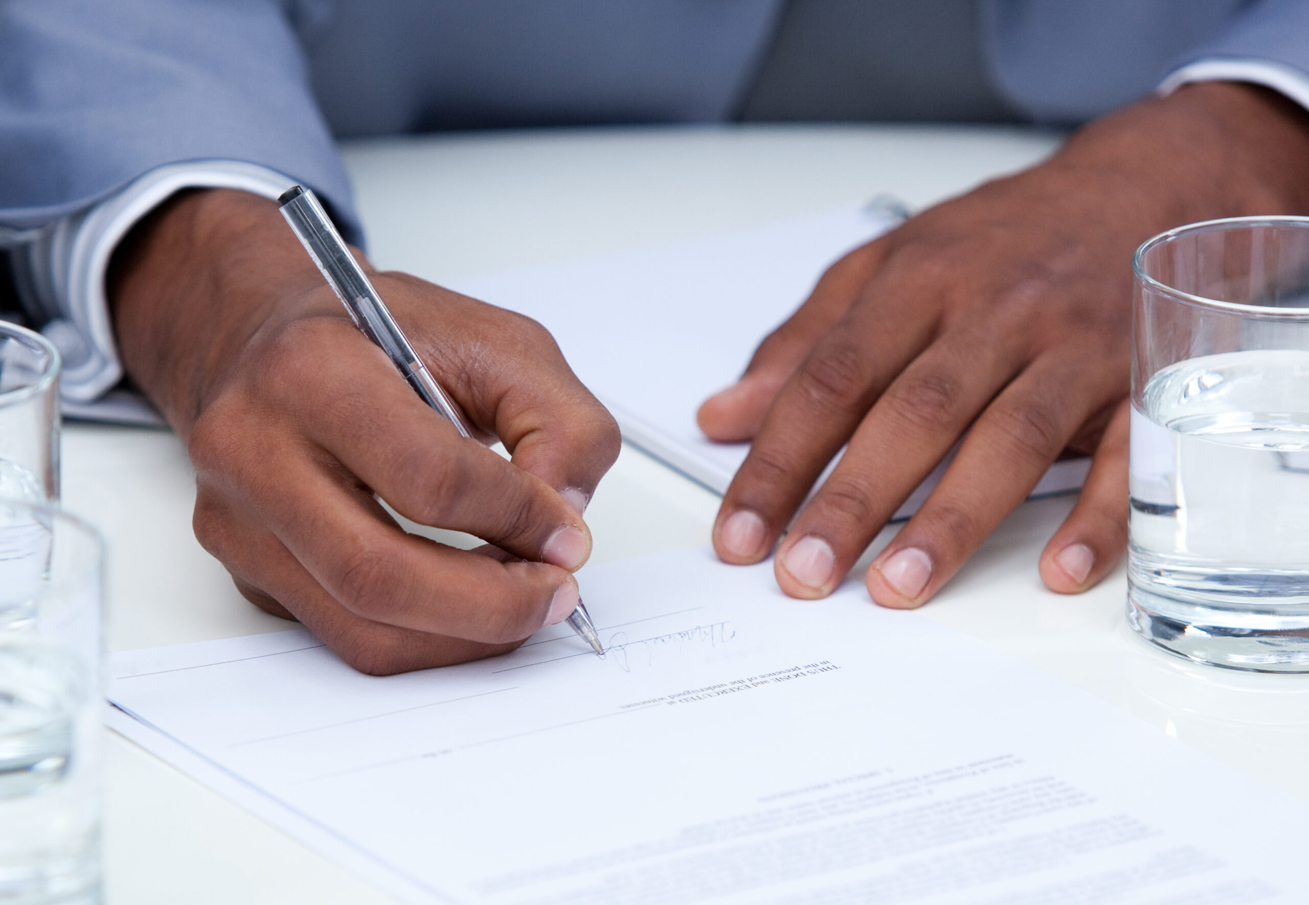 Close-up of ambitious business man signing legal contract in a company